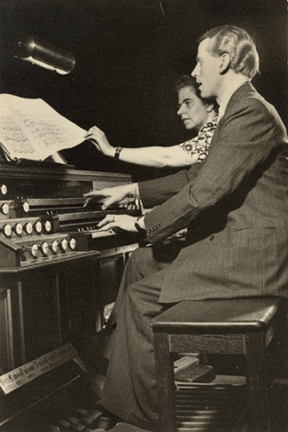 Piet van Egmond aan de speeltafel van het orgel in de Grote Zaal van het Concertgebouw te Amsterdam, geassisteerd door Nettie Spies. Foto uit juni 1949.